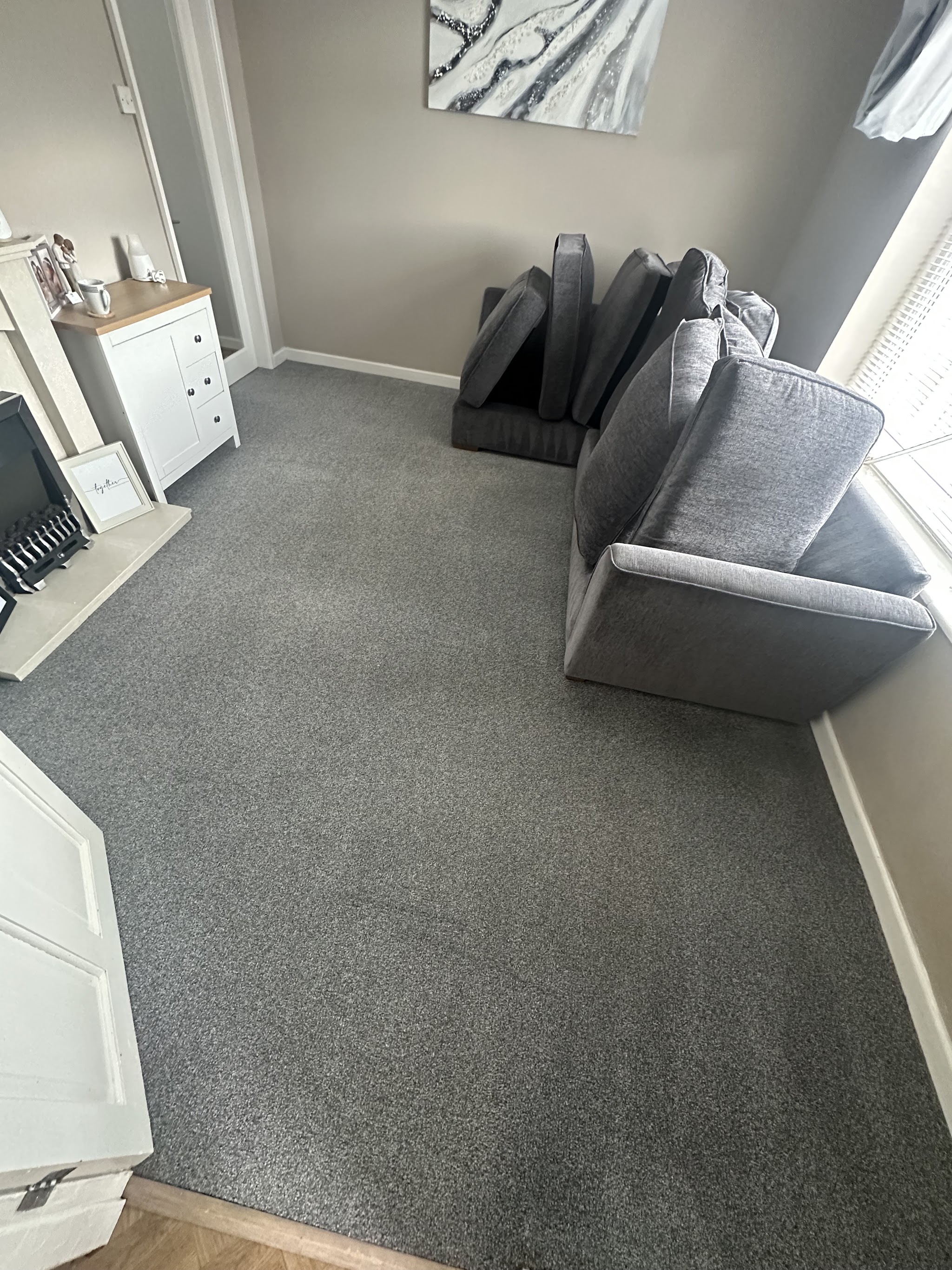 Freshly cleaned grey living room carpet with a sofa, photographed by a customer